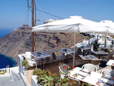 Mama Thira’s clifftop terrace in Firostefani, tables laid for dinner