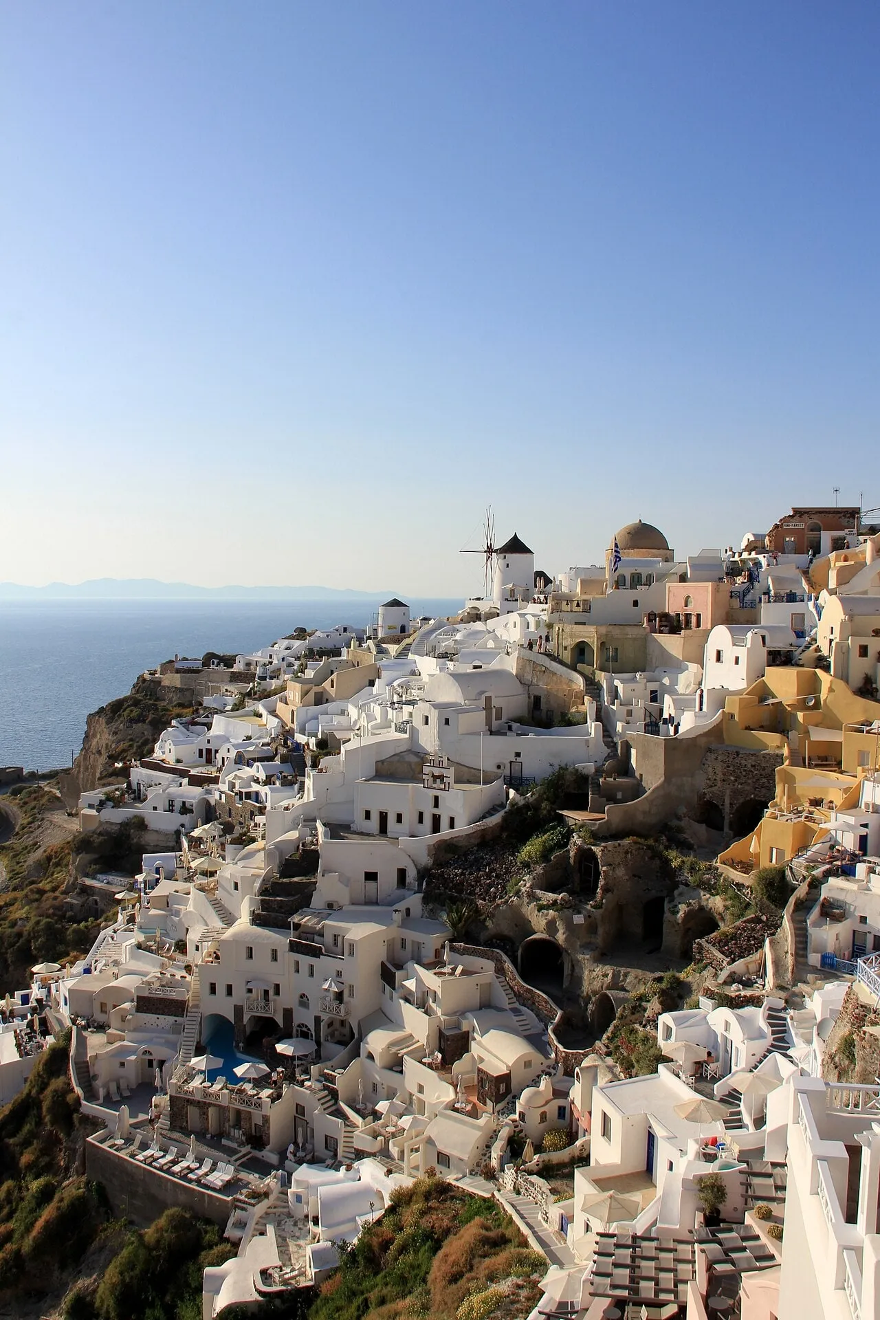 White houses stepping down the caldera cliff at Oia, a windmill above them