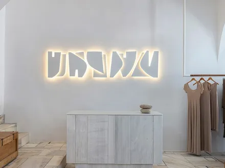 The Parthenis store in Mykonos: a white vaulted room with linen on a brass rail